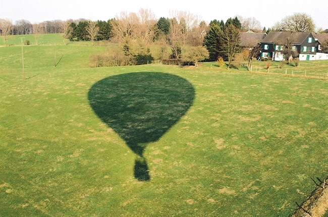 Schatten von Heißluftballon auf Wiese im Sommer